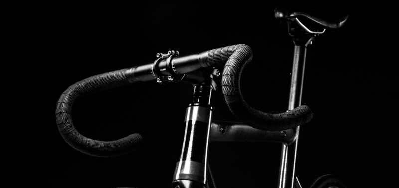 Nahaufnahme eines Fahrradlenkers und Sattels in schwarz-weiß vor einem dunklen Hintergrund.
